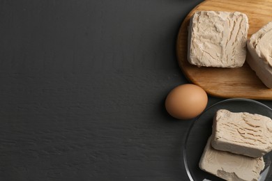 Compressed yeast and egg on grey wooden table, flat lay. Space for text