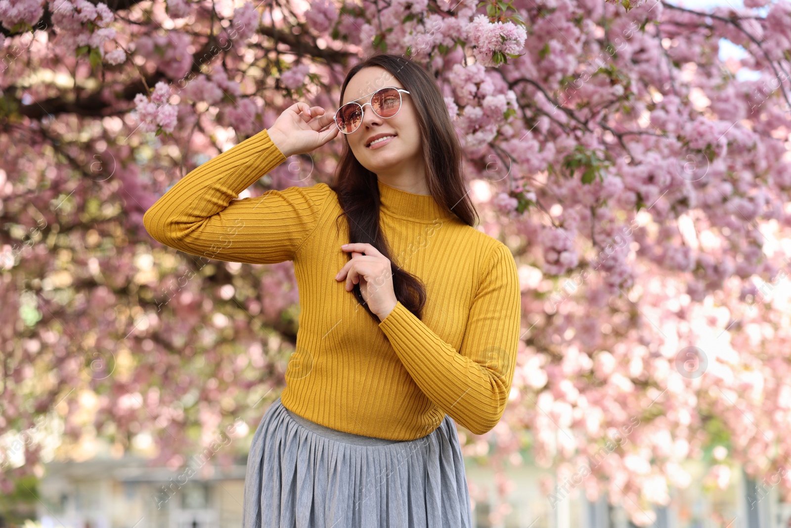 Photo of Beautiful woman in sunglasses near blossoming tree on spring day