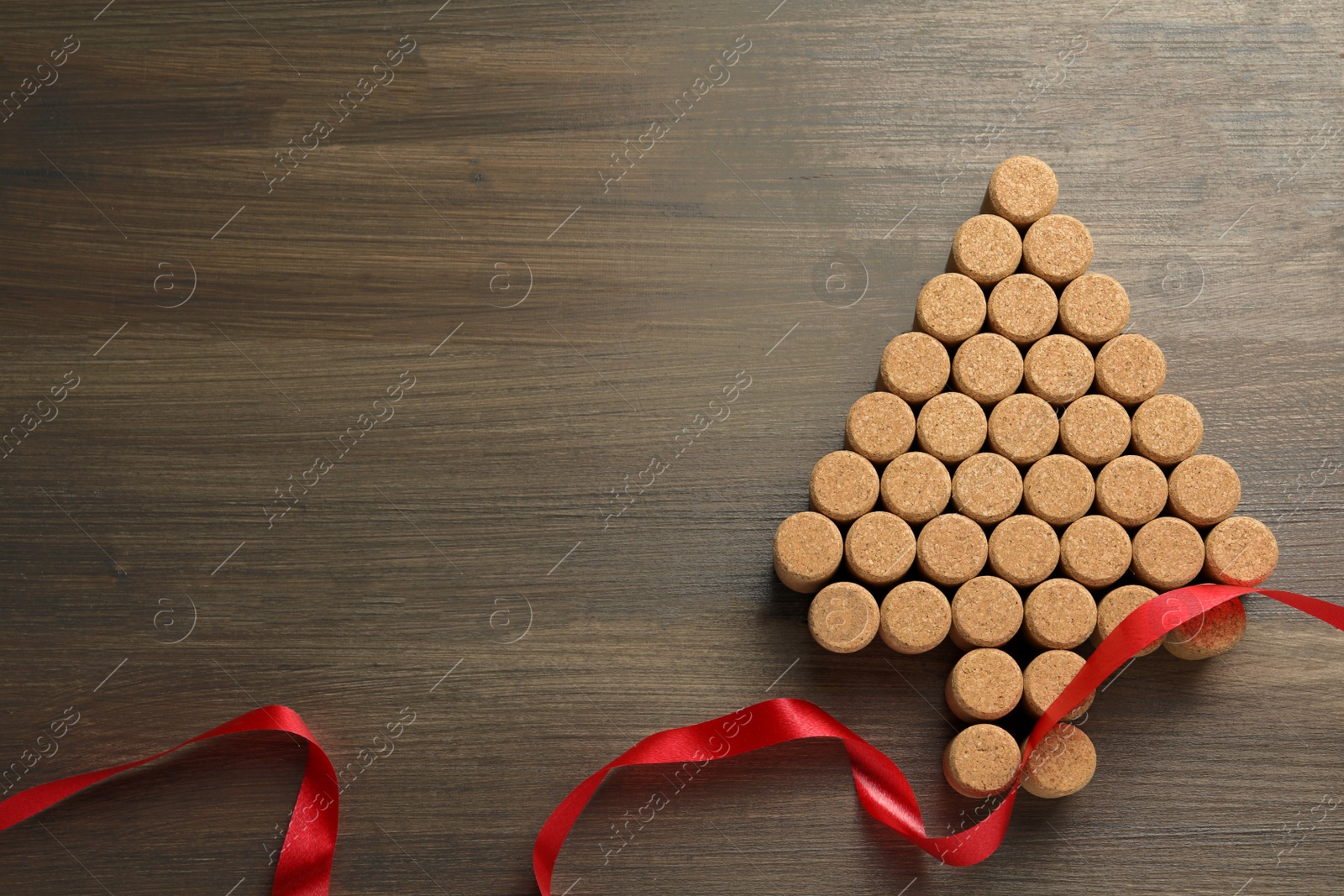 Photo of Christmas tree made of wine corks and red ribbon on wooden table, top view. Space for text