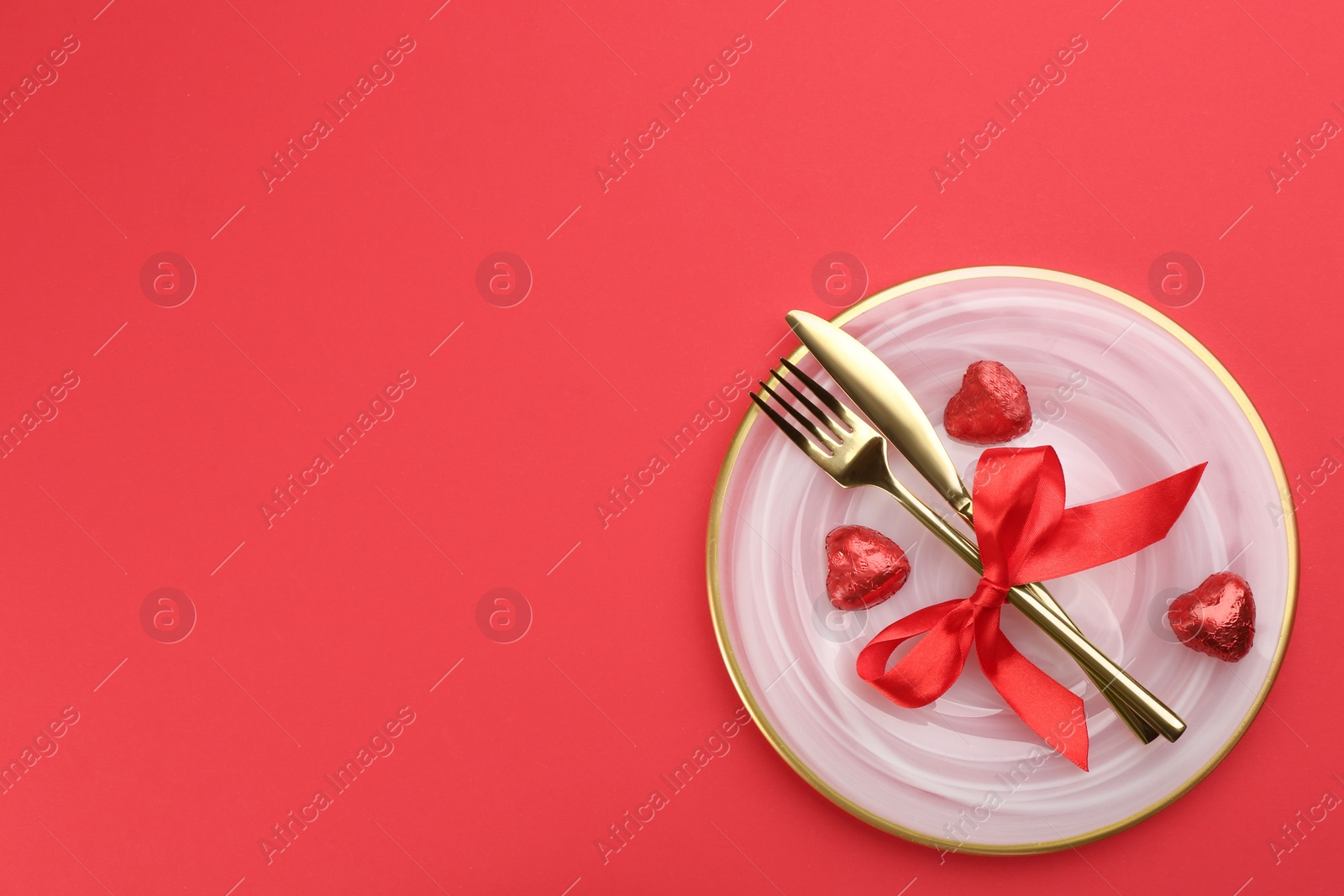 Photo of Beautiful table setting on red background, top view with space for text. Valentine's Day dinner