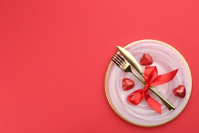 Photo of Beautiful table setting on red background, top view with space for text. Valentine's Day dinner