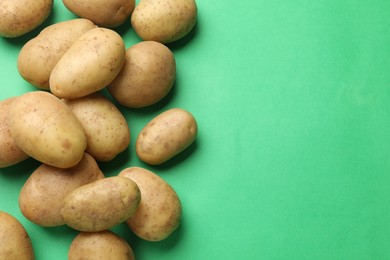 Photo of Fresh raw potatoes on green background, flat lay. Space for text