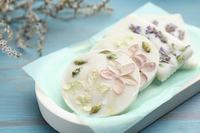 Tray with scented sachets on light blue wooden table, closeup