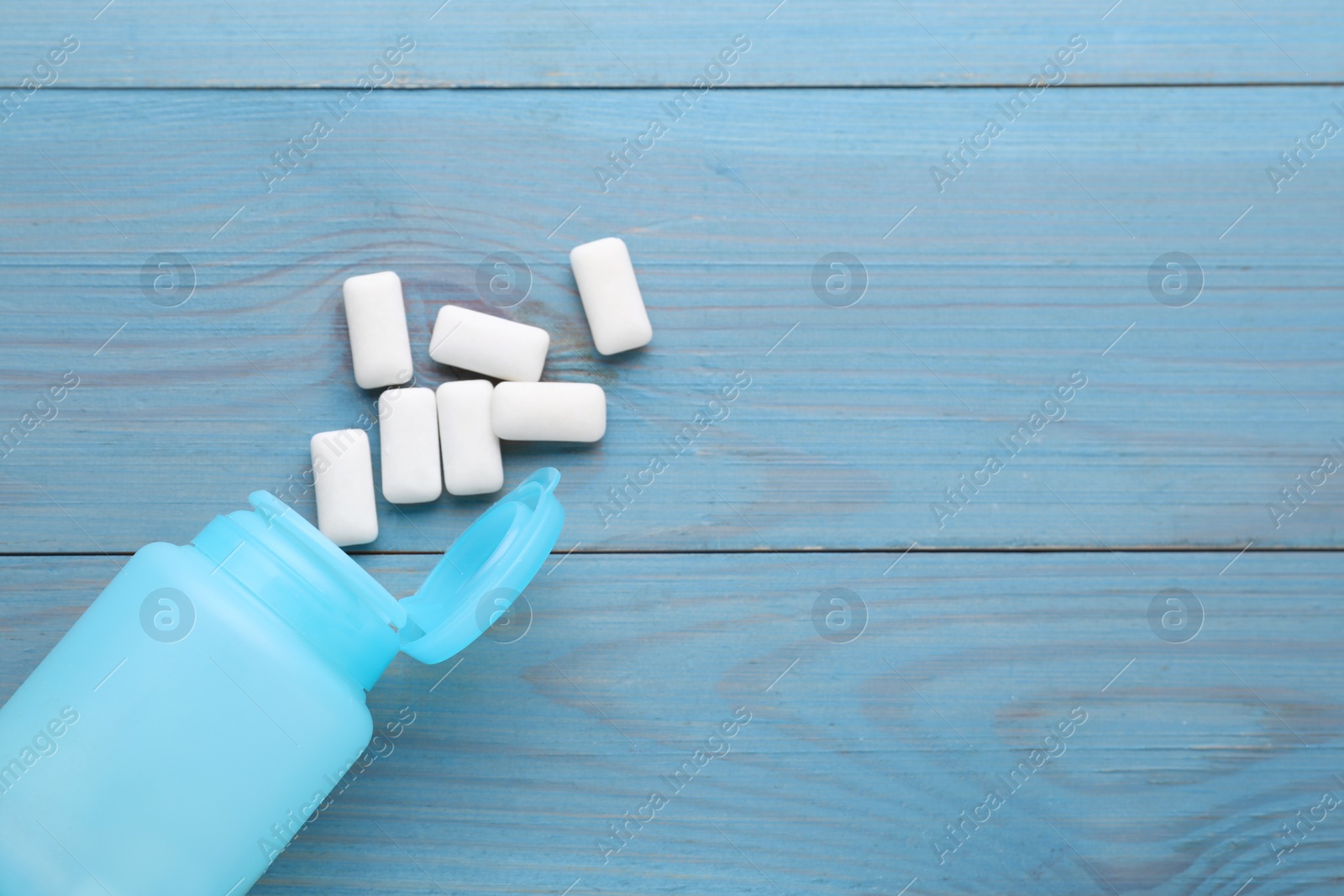 Photo of Jar with chewing gums on light blue wooden table, flat lay. Space for text