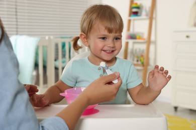 Photo of Mother feeding her cute little child with yogurt at home