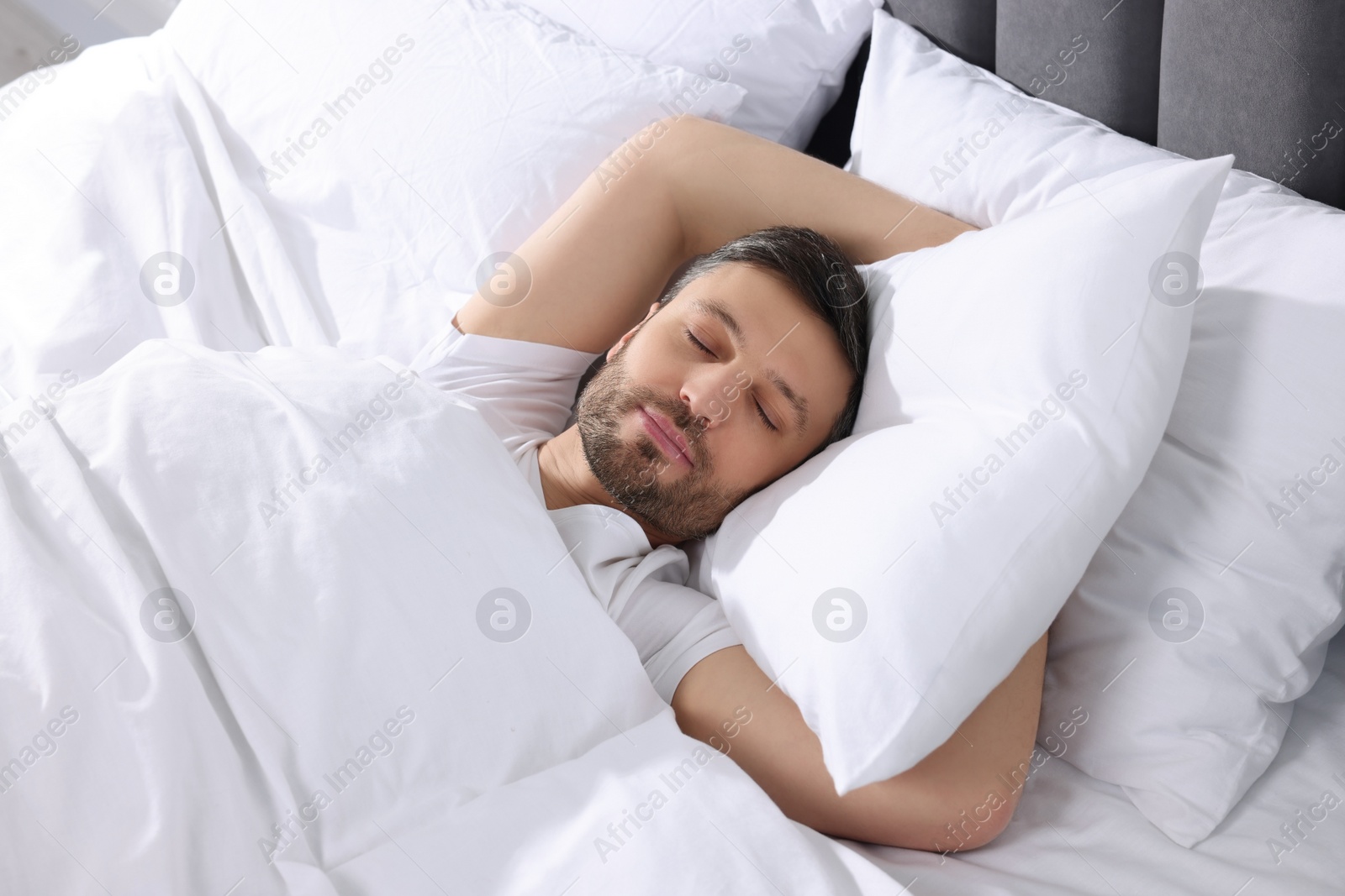 Photo of Handsome man sleeping in soft white bed