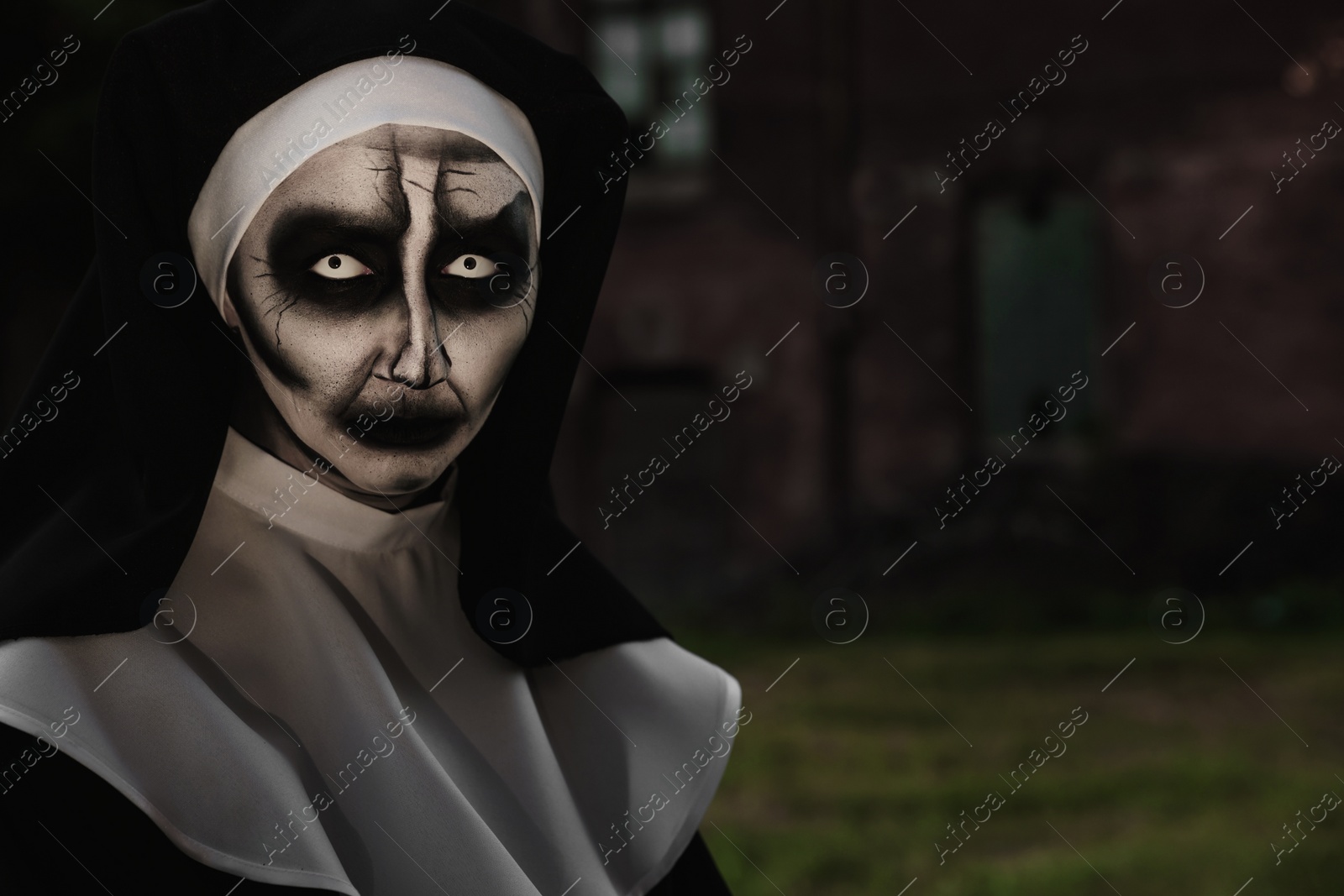 Photo of Portrait of scary devilish nun outdoors, space for text. Halloween party look