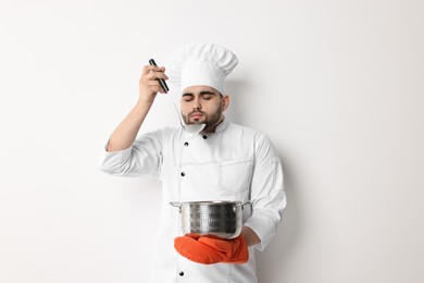 Professional chef smelling something on white background