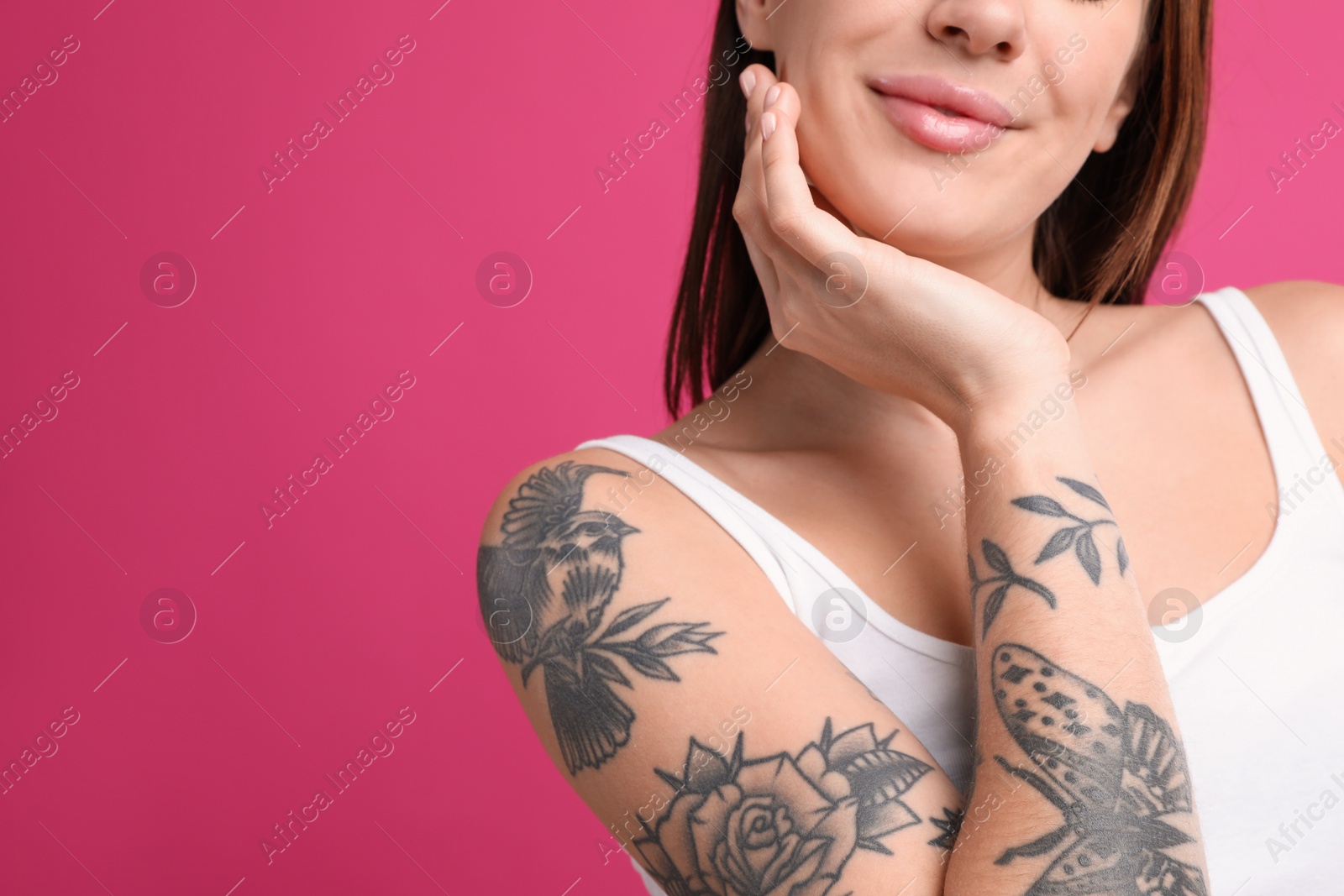 Photo of Beautiful woman with tattoos on arm against pink background, closeup. Space for text