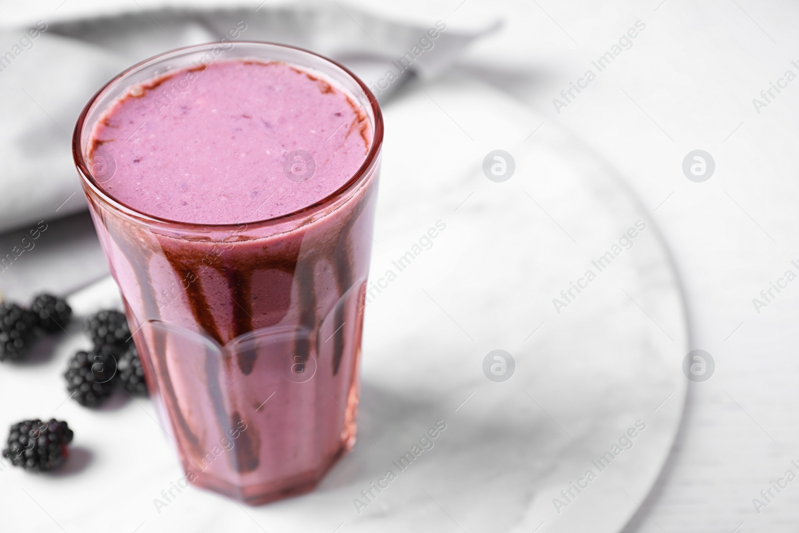 Photo of Tasty blackberry milk shake in glass on white table