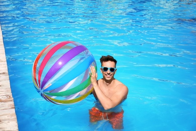 Happy young man with inflatable ball in swimming pool