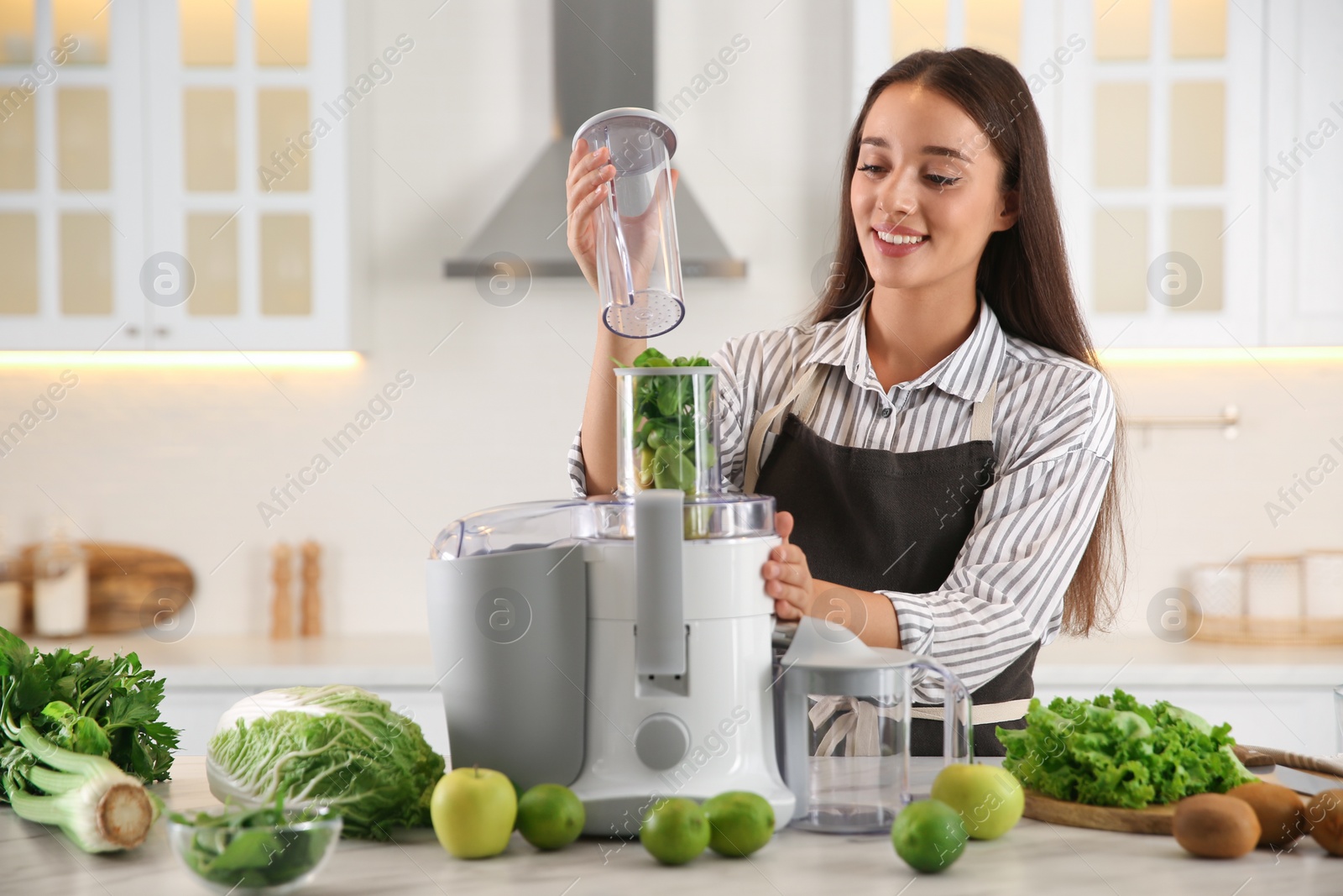 Photo of Young woman making tasty fresh juice at table in kitchen