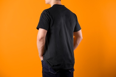 Young man in black t-shirt on color background. Mockup for design