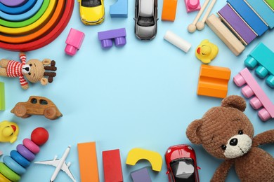 Photo of Frame of different children's toys on light blue background, flat lay. Space for text