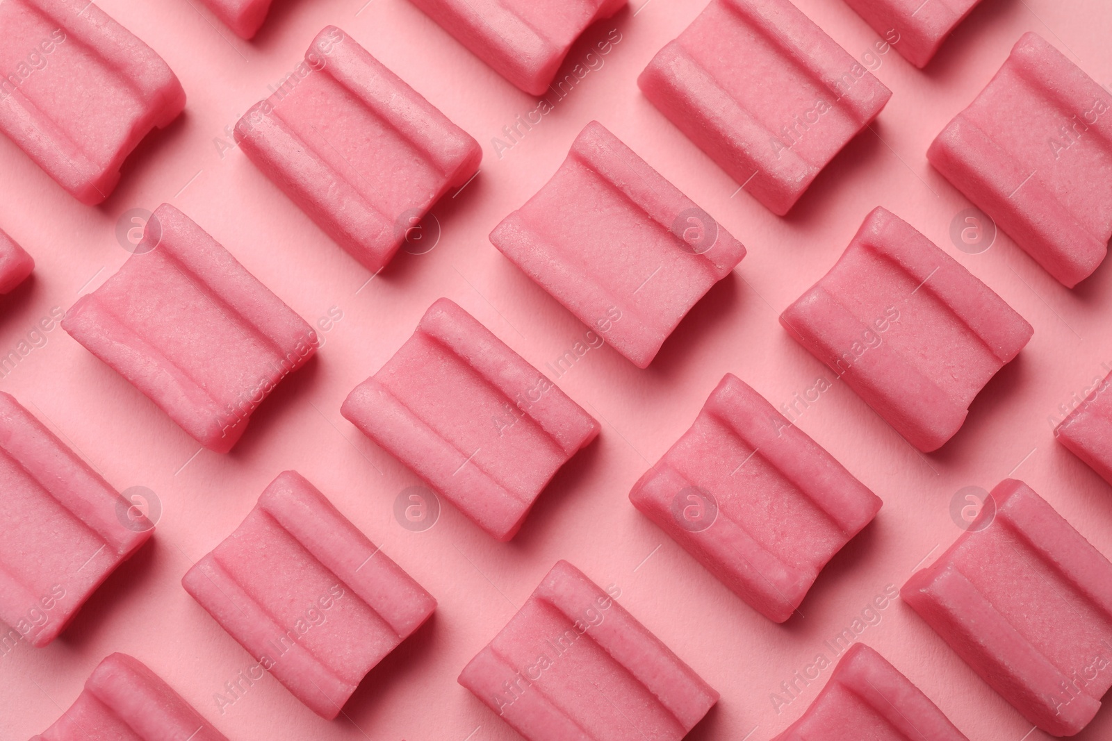 Photo of Tasty chewing gums on pink background, flat lay