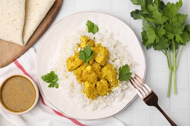 Photo of Delicious rice and chicken with curry sauce on white tiled table, flat lay