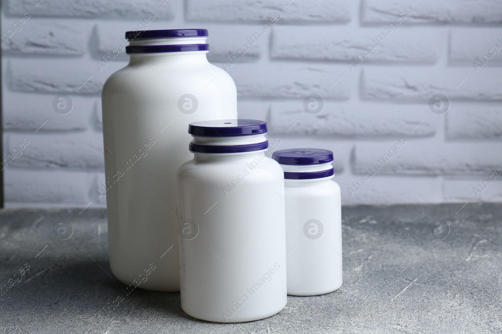 Photo of White medical bottles on light gray textured table