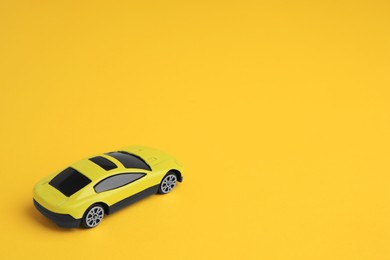 Photo of One bright car on yellow background, space for text. Children`s toy