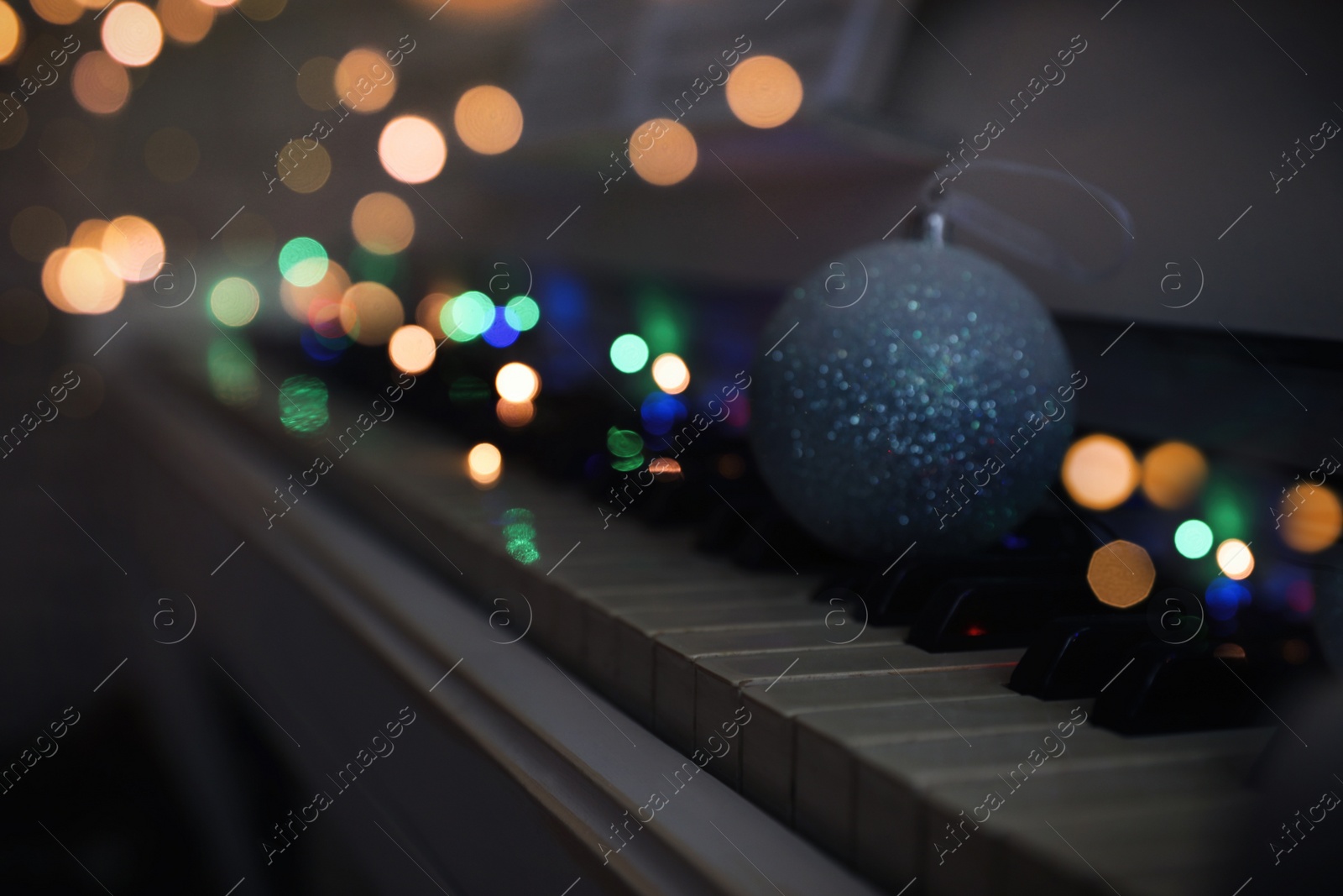 Photo of Beautiful bauble and fairy lights on piano keys, space for text. Christmas music