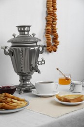 Vintage samovar, cup of hot drink and snacks served on table. Traditional Russian tea ceremony