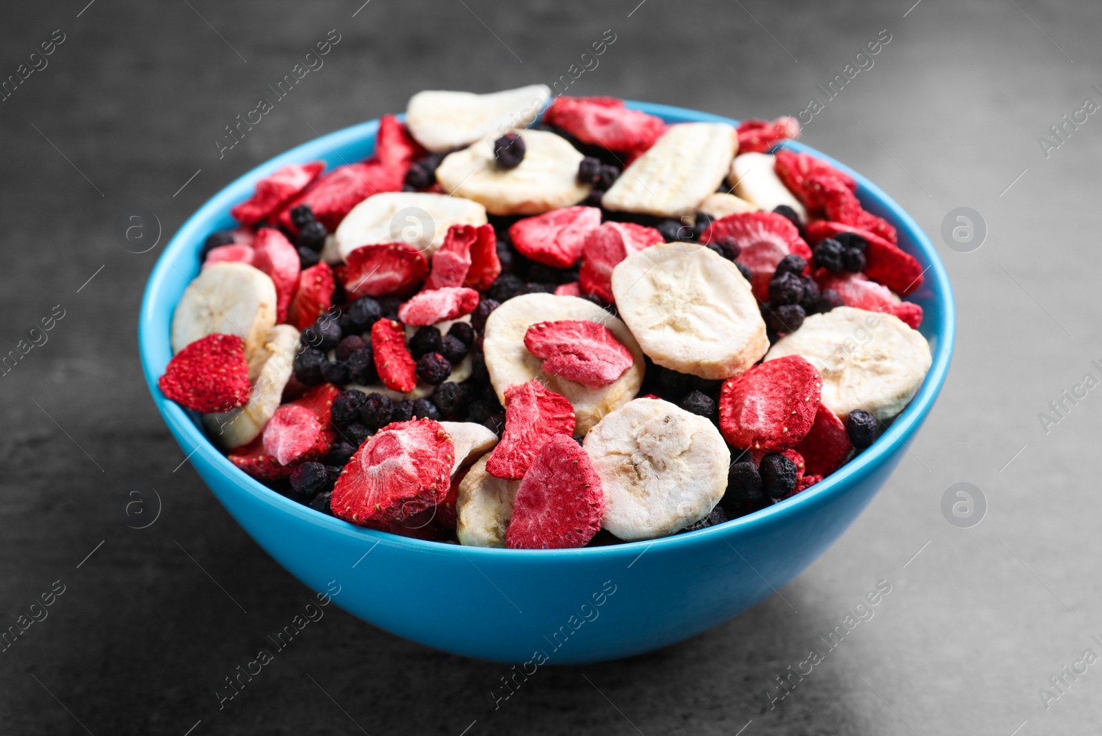 Photo of Bowl of dried fruits on grey table, closeup