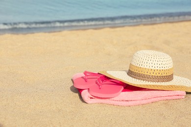 Photo of Beach towel with straw hat and slippers on sand near sea