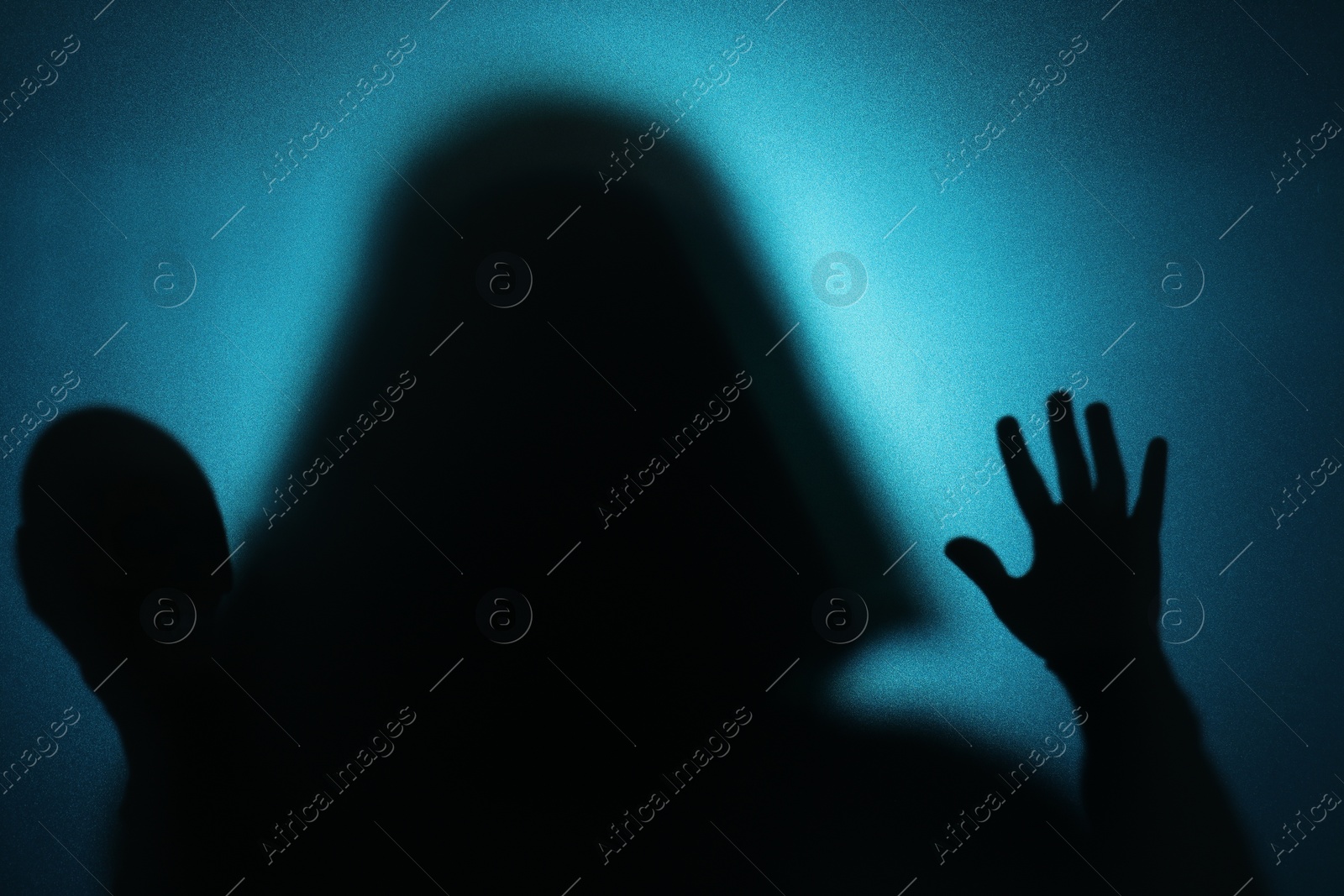 Photo of Silhouette of ghost behind glass against blue background