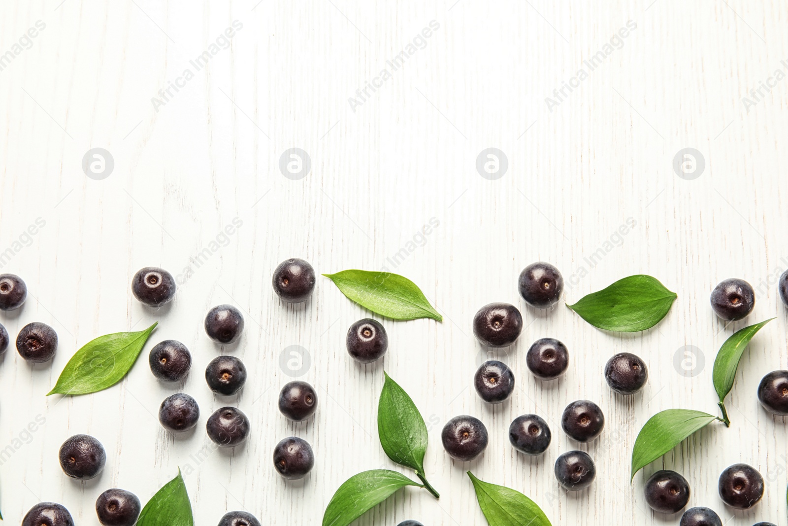 Photo of Flat lay composition with fresh acai berries and leaves on wooden background