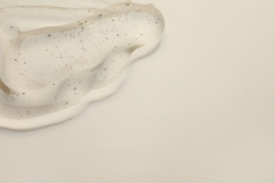 Photo of Sample of cosmetic oil on beige background, closeup. Space for text