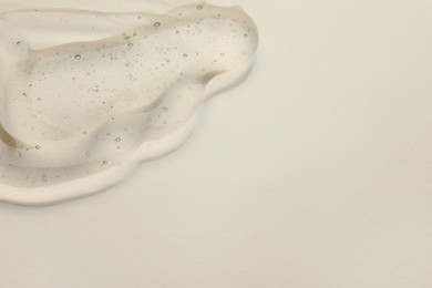 Sample of cosmetic oil on beige background, closeup. Space for text