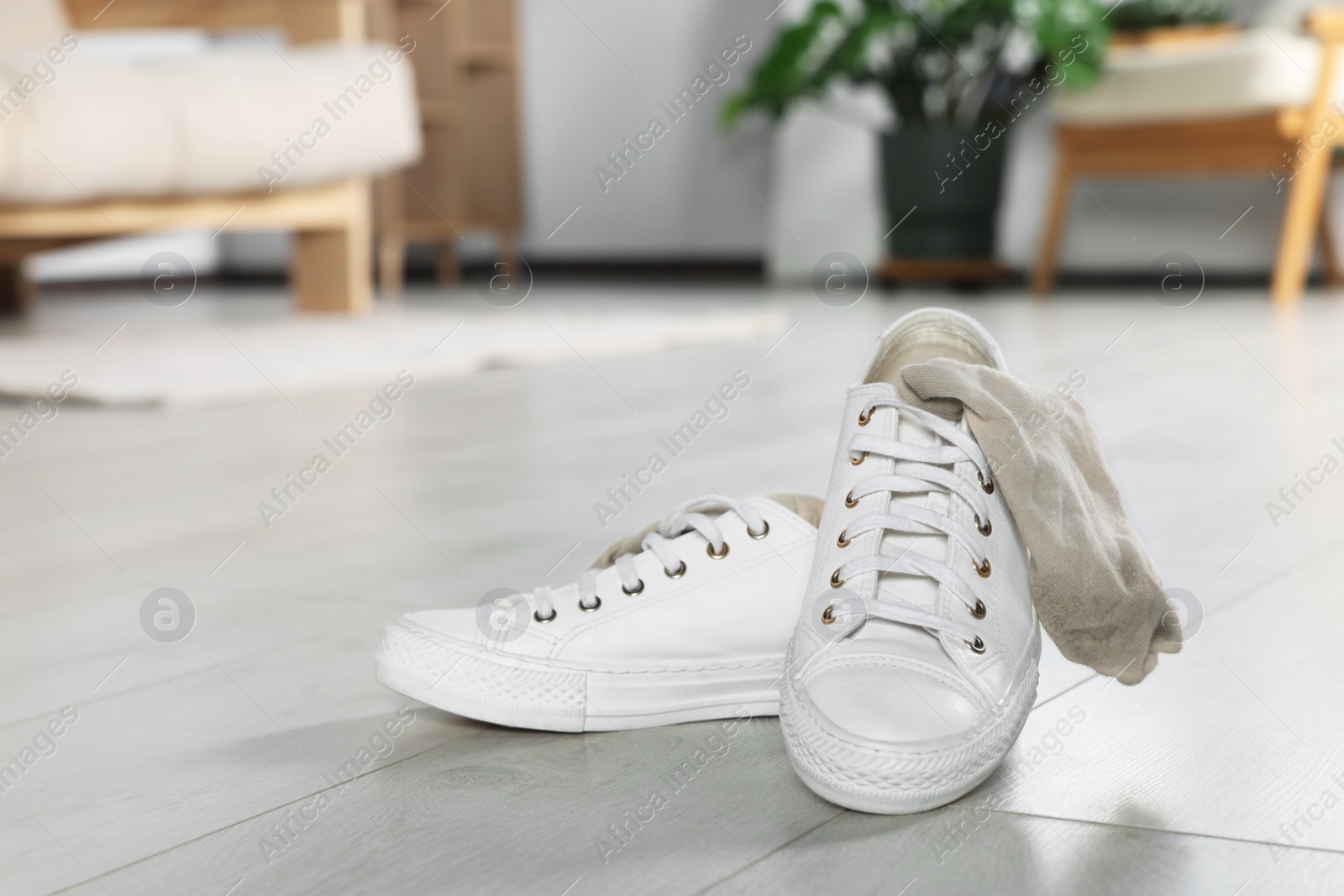 Photo of Sneakers with dirty socks on white wooden floor indoors