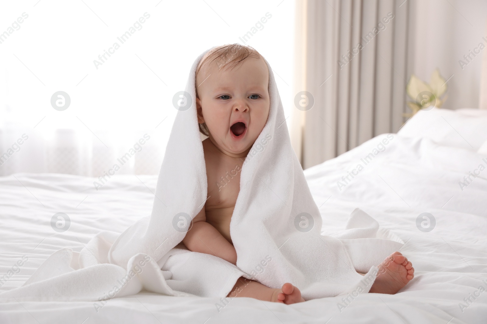 Photo of Cute little baby with soft towel on bed after bath