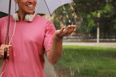 Photo of Man with umbrella walking under rain in park, closeup