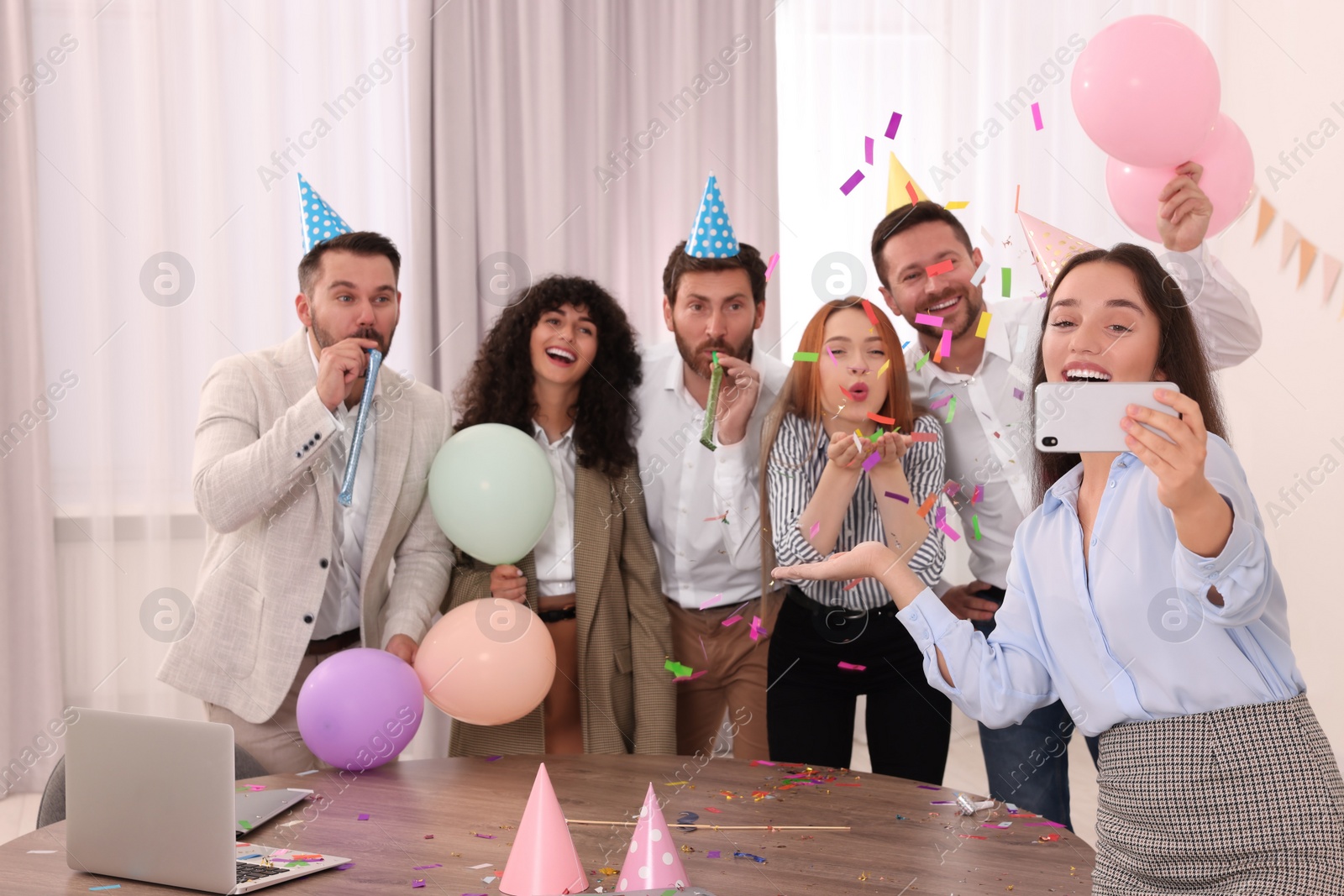 Photo of Coworkers taking selfie during office party indoors