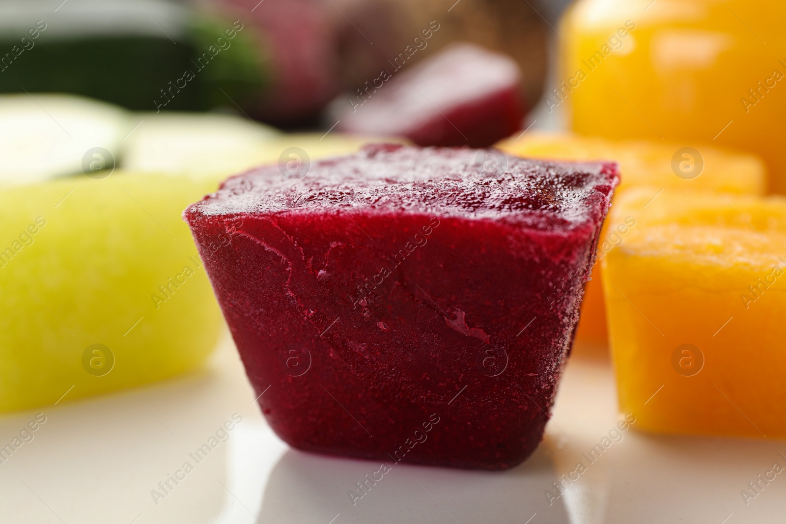 Photo of Frozen beet, pumpkin and zucchini puree cubes on plate, closeup