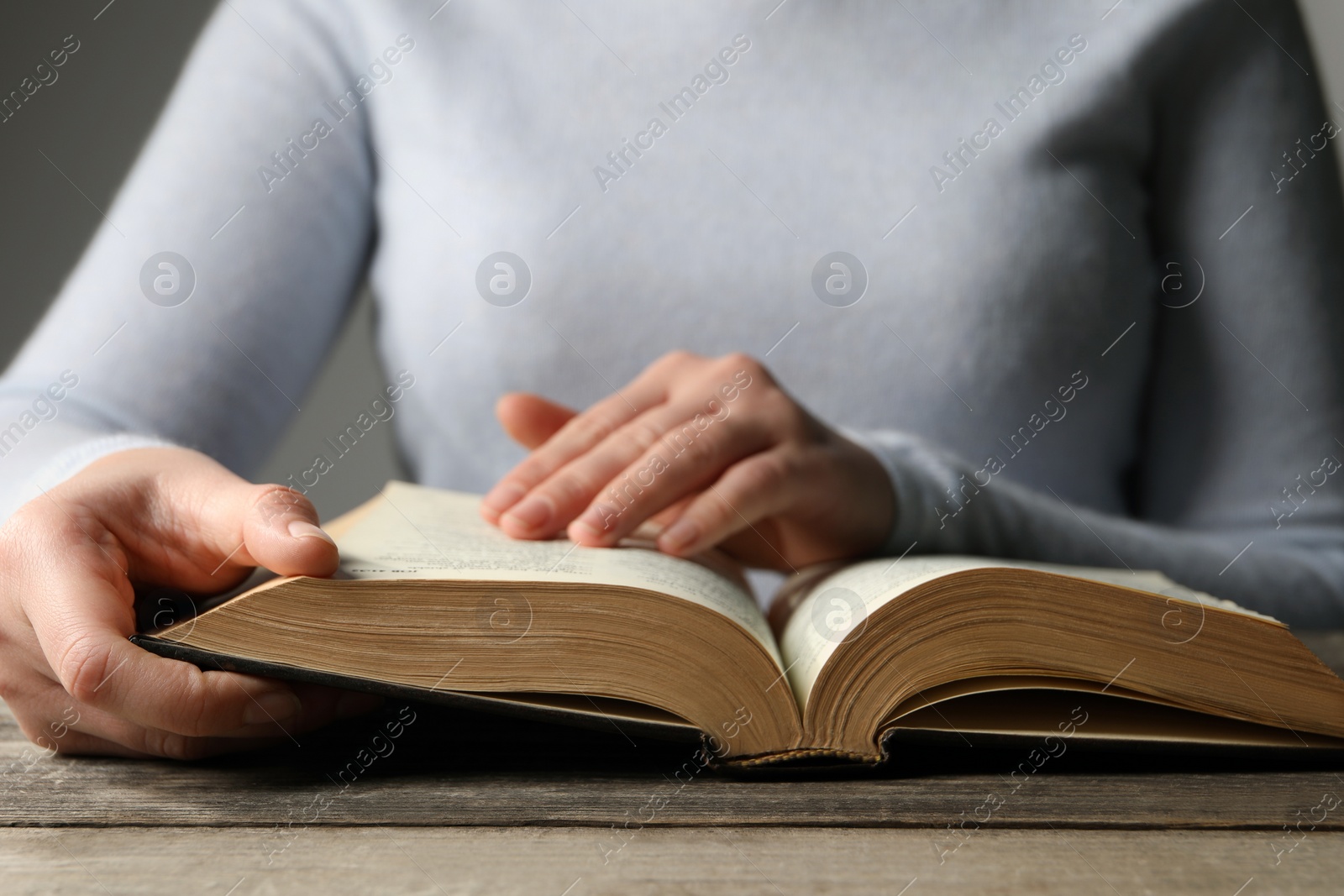 Photo of Woman reading Bible at wooden table, closeup