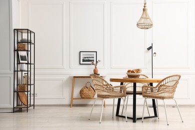 Dining room interior with wooden table and wicker chairs