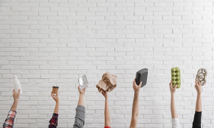 Photo of People holding different garbage against brick wall. Waste recycling concept