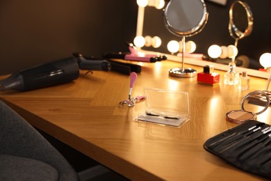 Photo of Eyelashes, different makeup products and tools on wooden table indoors