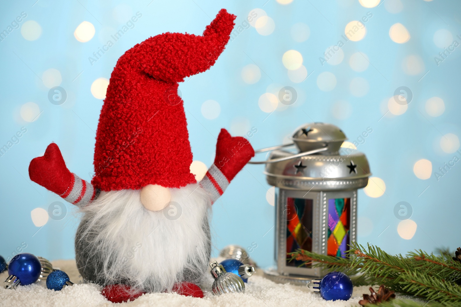 Photo of Cute Christmas gnome and festive decor on snow against blurred lights