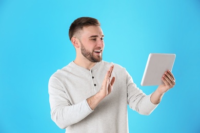 Young man using video chat on tablet against color background