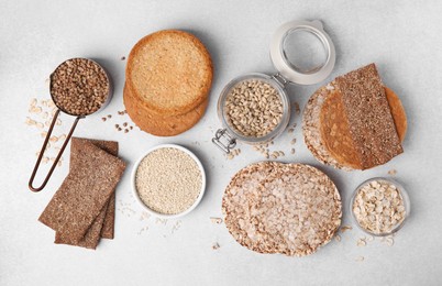 Photo of Rye crispbreads, rice cakes and rusks on white table, flat lay