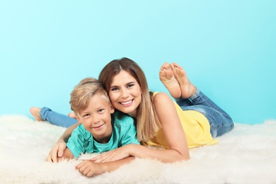 Mother and son lying on fuzzy rug near color wall