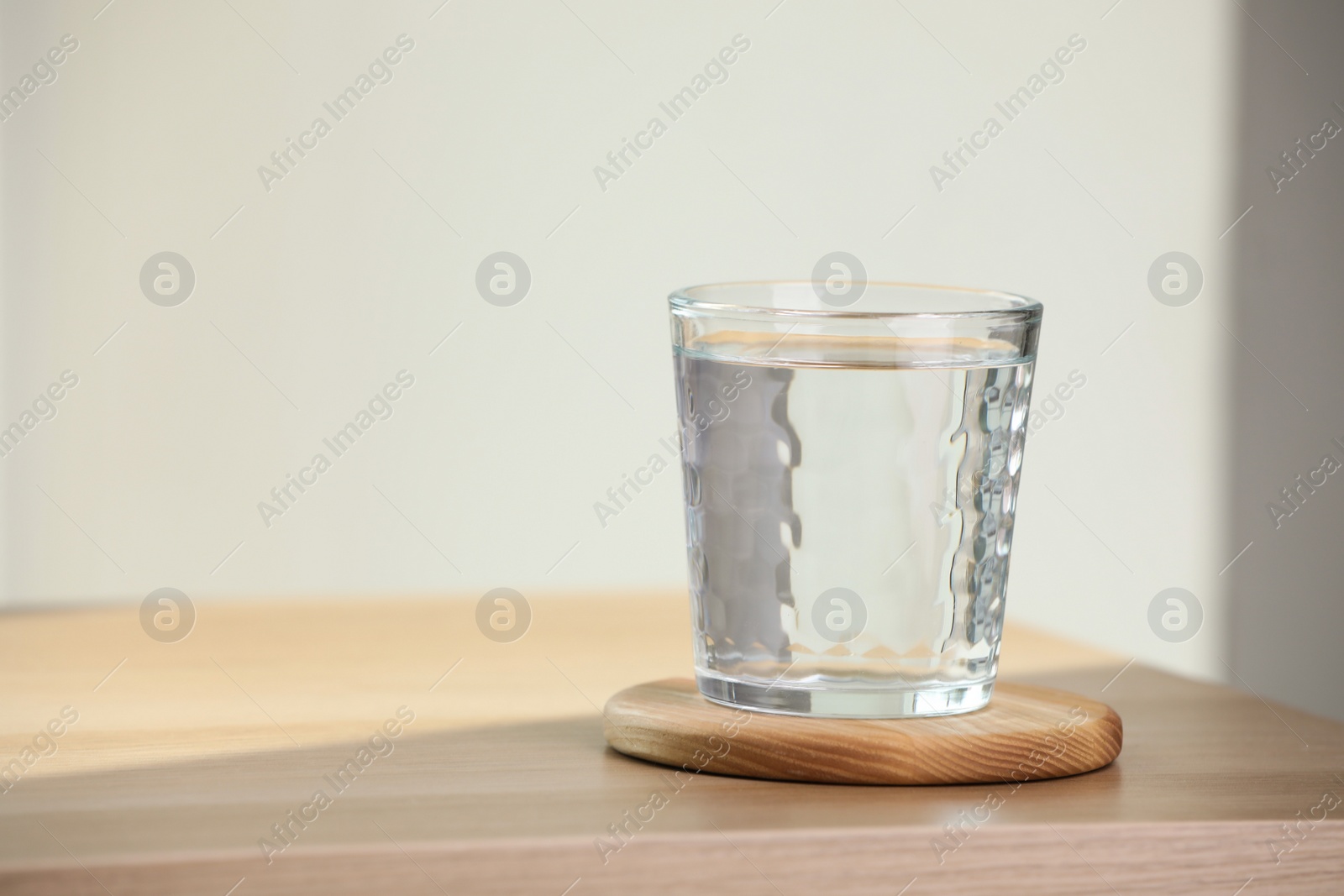 Photo of Glass of pure water on wooden table indoors, space for text