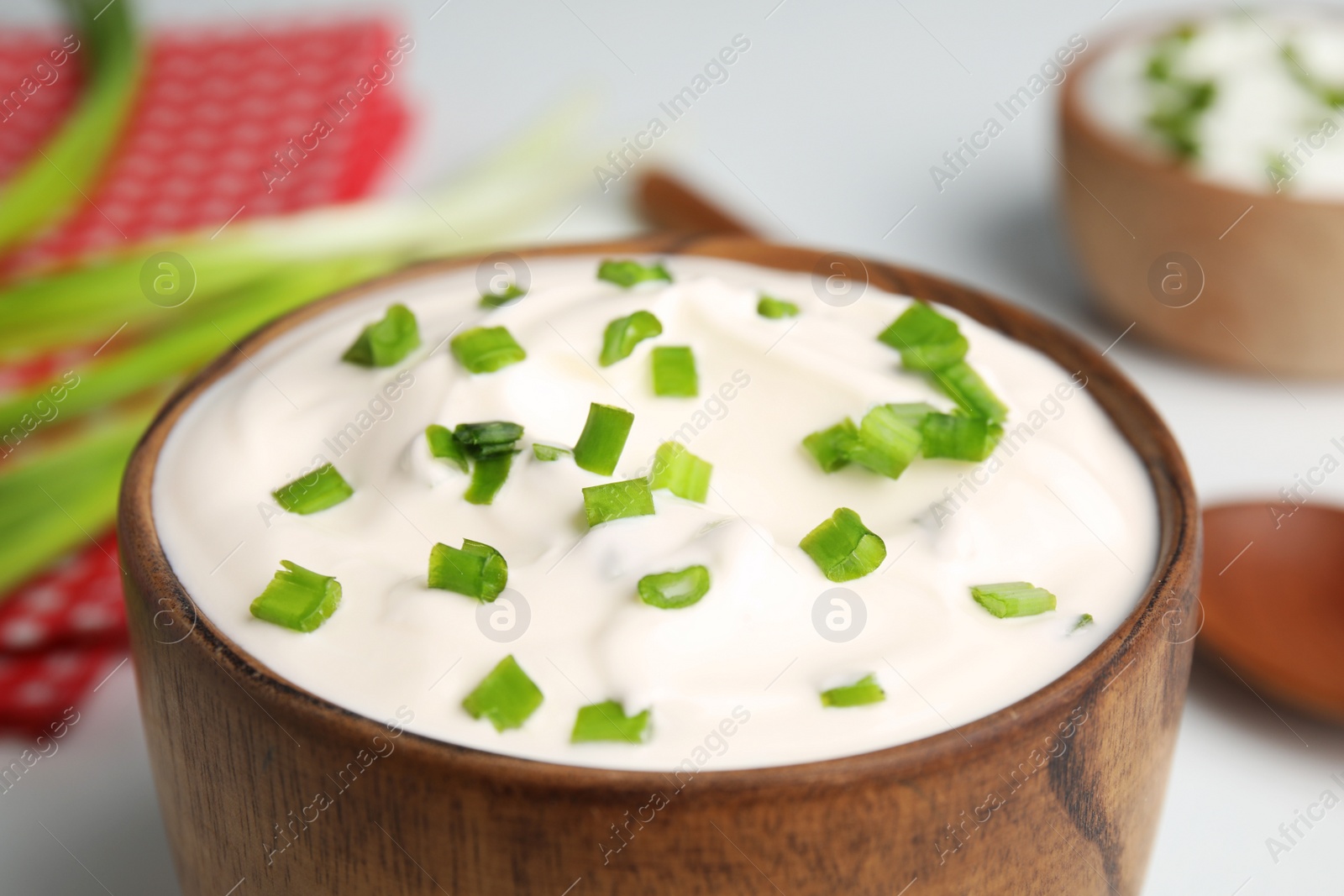 Photo of Fresh sour cream with onion in wooden bowl, closeup
