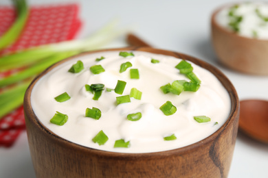 Fresh sour cream with onion in wooden bowl, closeup