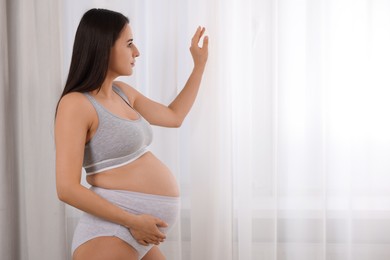 Photo of Beautiful pregnant woman in comfortable maternity underwear indoors, space for text