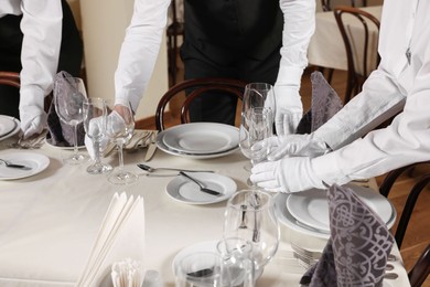 People setting table during professional butler courses in restaurant, closeup