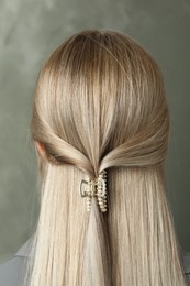 Photo of Young woman with beautiful hair claw on grey background, back view