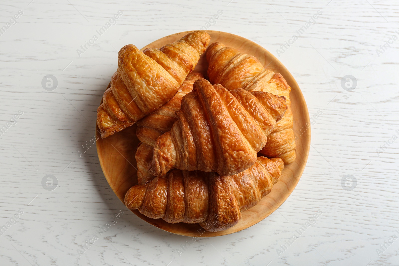 Photo of Plate with tasty croissants on white wooden background, top view. French pastry